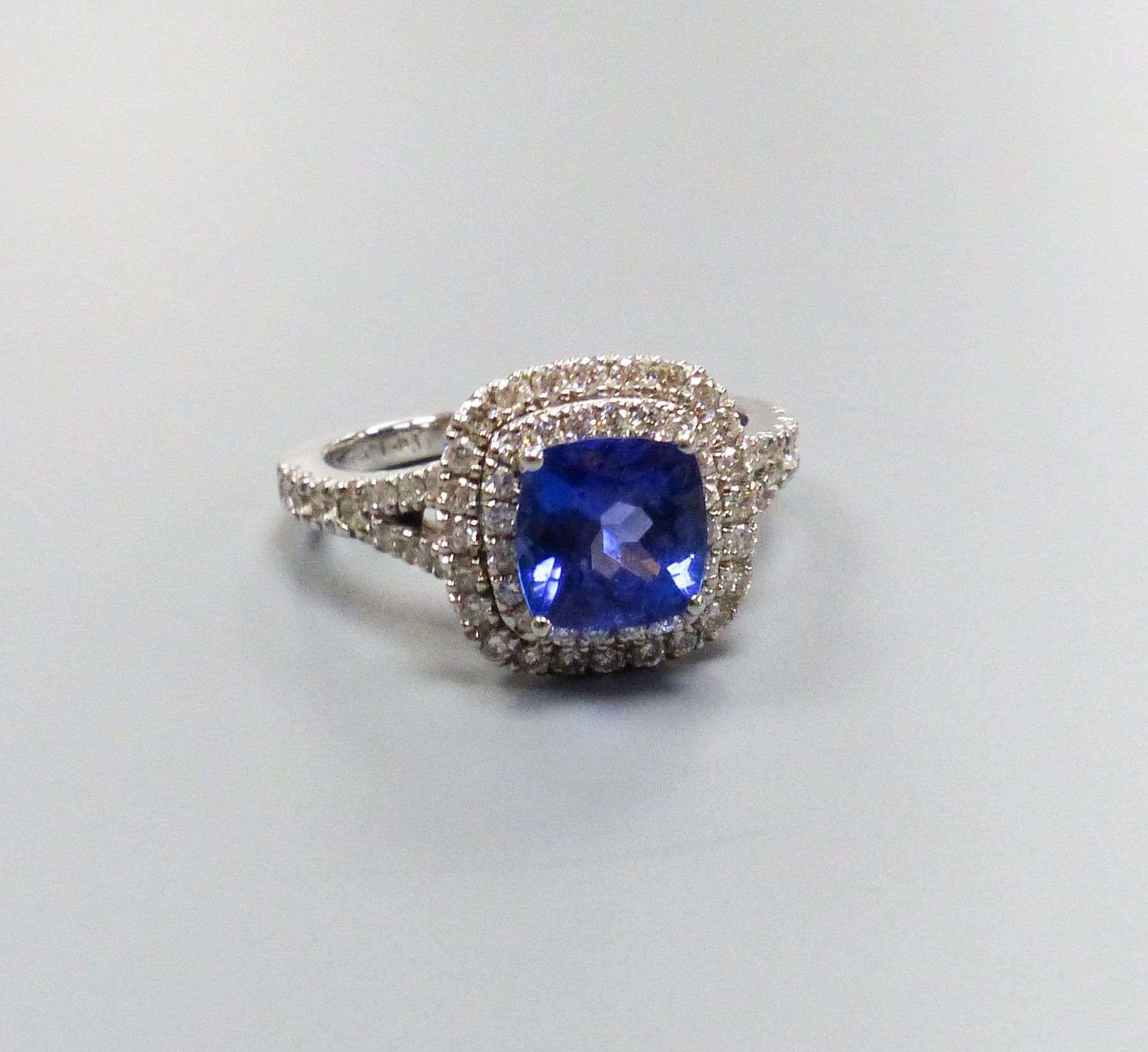 A modern 14k white metal, tanzanite and diamond set square cluster ring, with diamond set split shoulders, size M/N, gross weight 4.2 grams, the tanzanite weighing 1.63ct